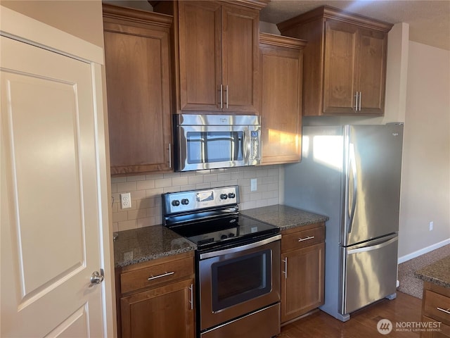 kitchen featuring appliances with stainless steel finishes, decorative backsplash, and dark stone countertops