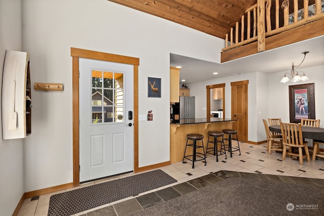 tiled foyer entrance featuring a notable chandelier, a high ceiling, and wood ceiling