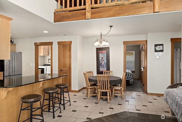 tiled dining space with separate washer and dryer and an inviting chandelier