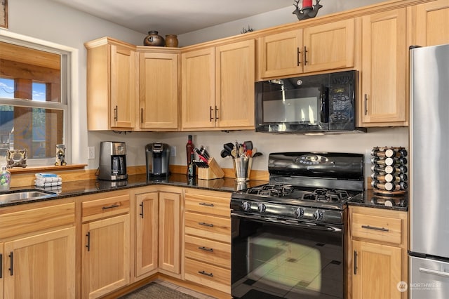 kitchen featuring dark stone countertops, light brown cabinets, black appliances, and sink