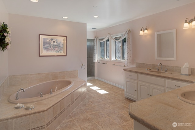 bathroom with tile floors, tiled tub, and vanity