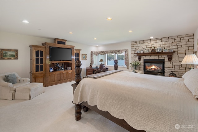 carpeted bedroom featuring a stone fireplace