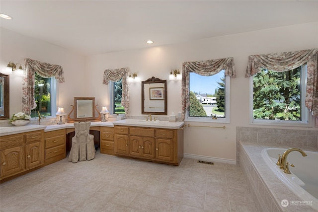 bathroom featuring a healthy amount of sunlight, tiled tub, vanity, and tile floors