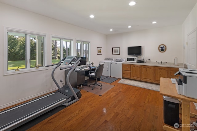 workout room with washing machine and dryer, sink, and light wood-type flooring