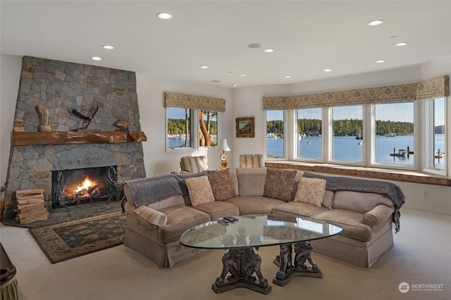 living room with a water view, carpet, and a fireplace