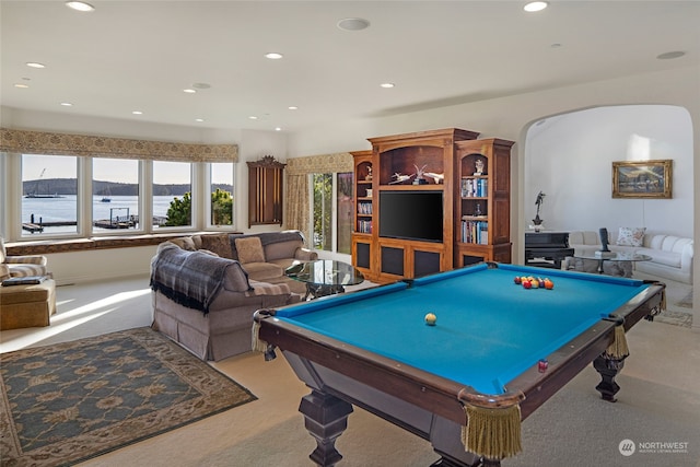 game room with light colored carpet, pool table, and a water view