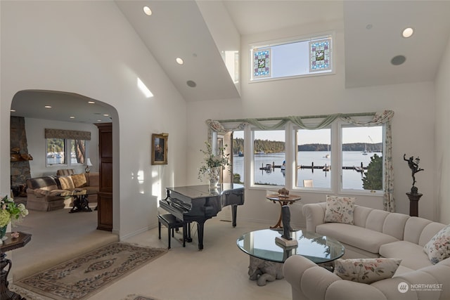 living room featuring high vaulted ceiling, carpet flooring, and a water view