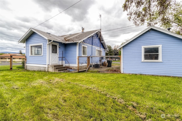 back of property featuring central AC unit and a lawn