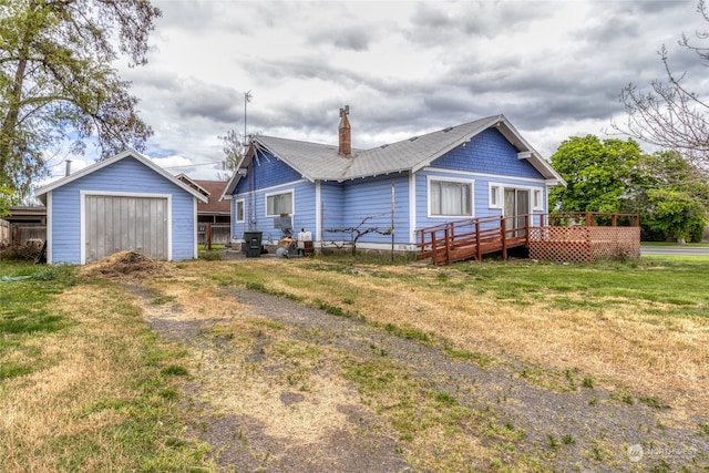 view of front of home with an outbuilding, a wooden deck, and a front lawn