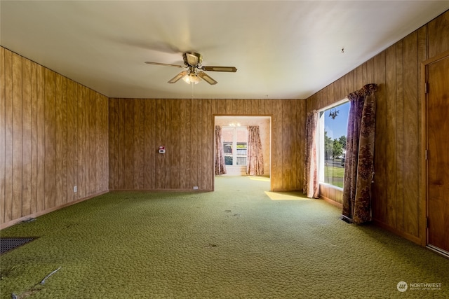 unfurnished room with ceiling fan, wooden walls, and carpet flooring