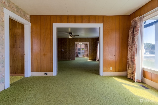 spare room with wood walls, carpet, and ceiling fan