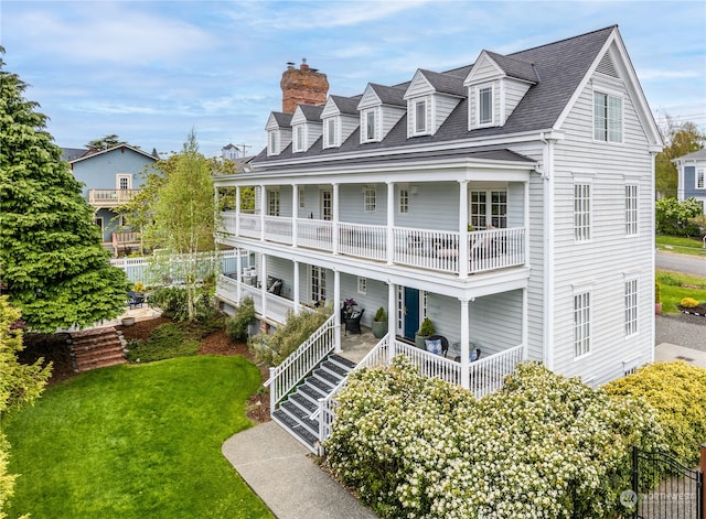 new england style home featuring a front yard and a balcony