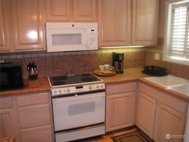 kitchen featuring backsplash, tile counters, white appliances, and light tile flooring