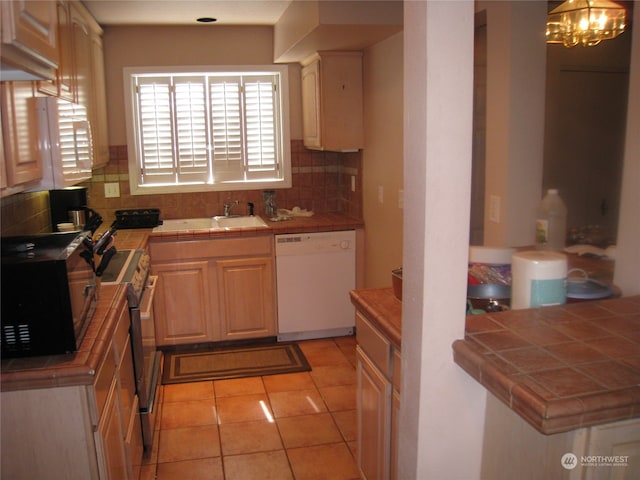 kitchen with tile counters, tasteful backsplash, white dishwasher, and range with electric cooktop