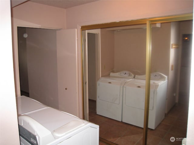 clothes washing area featuring dark tile flooring and washing machine and clothes dryer