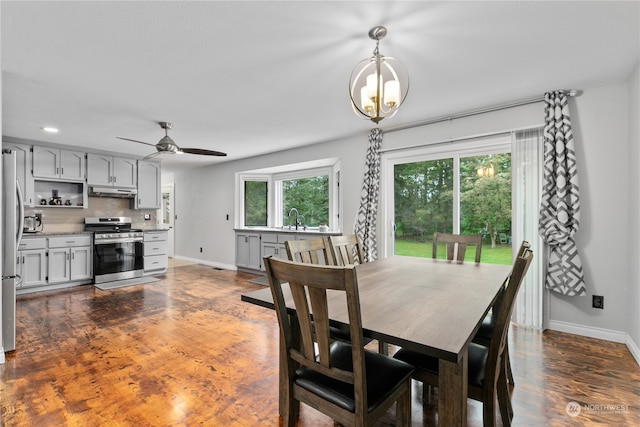 dining space with ceiling fan with notable chandelier, dark hardwood / wood-style floors, and sink