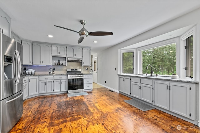 kitchen featuring dark wood-type flooring, stainless steel appliances, sink, tasteful backsplash, and ceiling fan