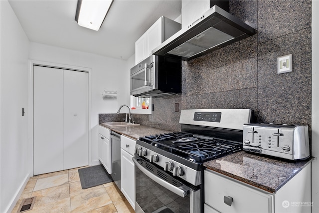 kitchen featuring stainless steel appliances, wall chimney range hood, white cabinets, sink, and light tile floors