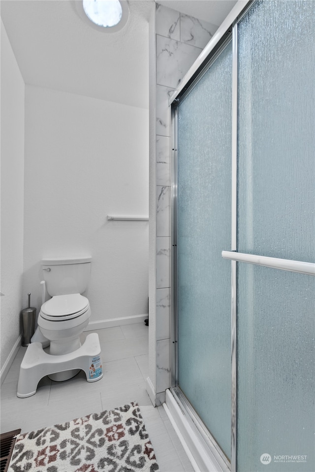 bathroom with a shower with shower door, toilet, and tile flooring