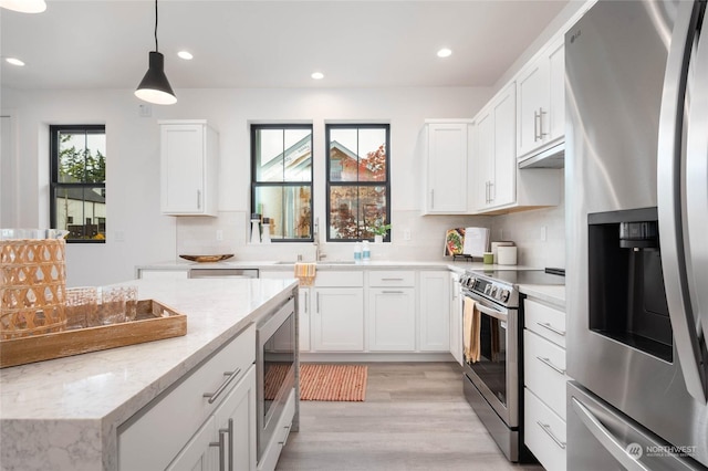 kitchen featuring appliances with stainless steel finishes, sink, hanging light fixtures, and white cabinets