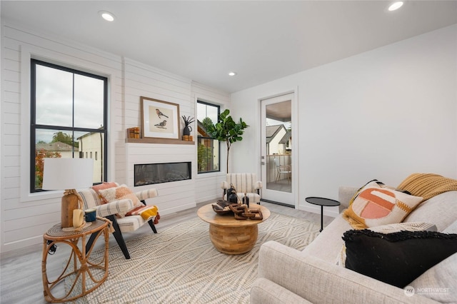 living room with radiator heating unit, light hardwood / wood-style floors, a large fireplace, and a healthy amount of sunlight