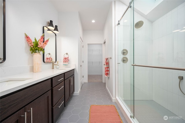 bathroom with tile patterned floors, vanity, walk in shower, and a skylight