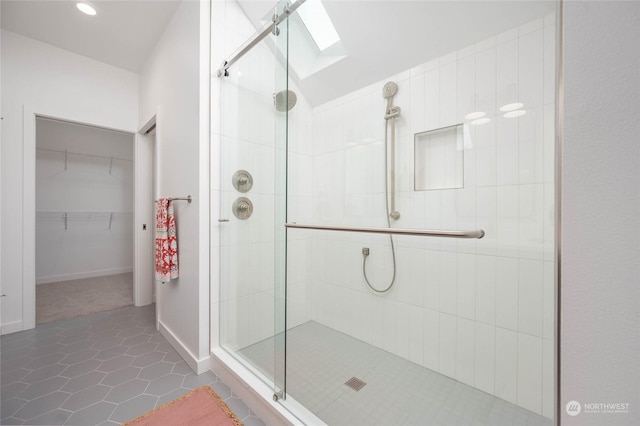 bathroom featuring tile patterned flooring, a skylight, and a shower with shower door