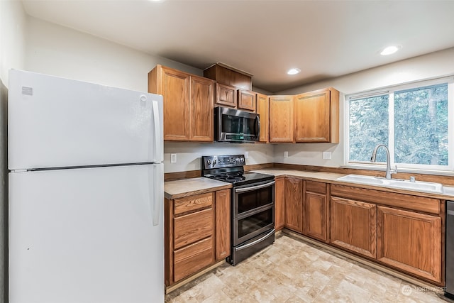 kitchen with dishwashing machine, light tile flooring, range with two ovens, white fridge, and sink