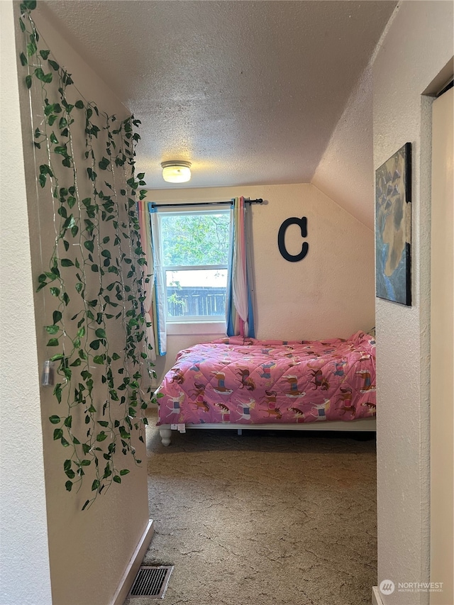 bedroom with vaulted ceiling, carpet flooring, and a textured ceiling