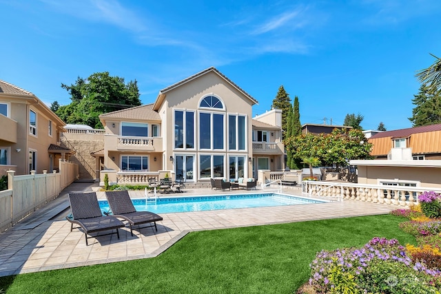 rear view of property with a patio area, a balcony, and a lawn