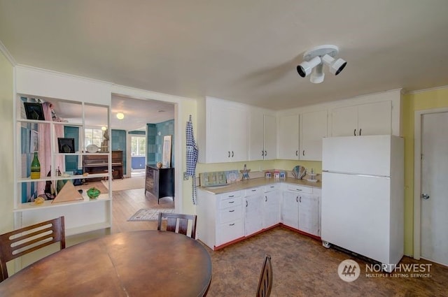 kitchen with white refrigerator and white cabinetry