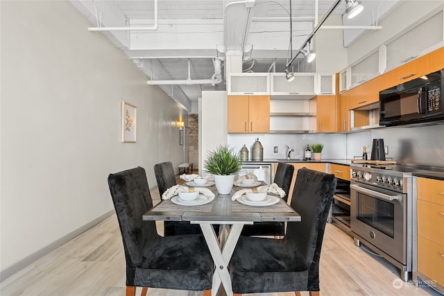 dining room with sink, a towering ceiling, and light hardwood / wood-style floors