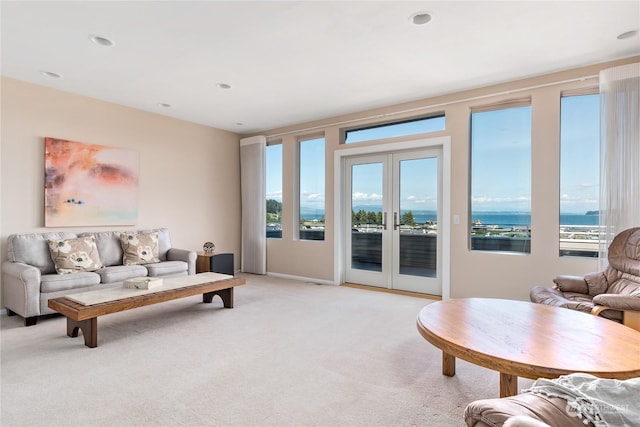 carpeted living room featuring french doors and a water view