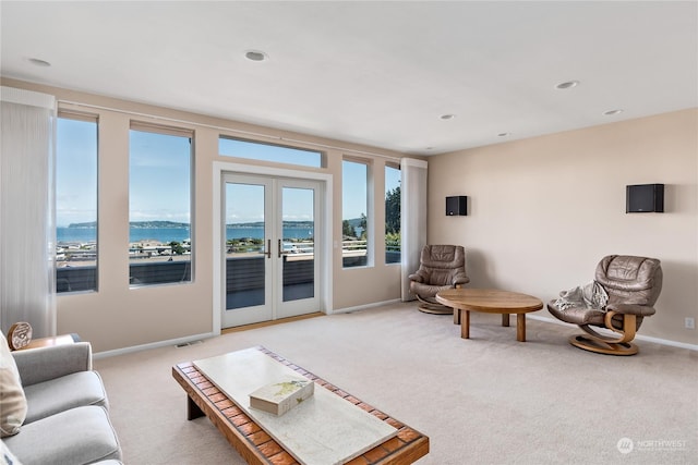 carpeted living room with a water view and french doors