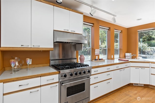 kitchen featuring kitchen peninsula, white cabinetry, stainless steel stove, and rail lighting