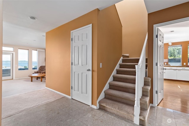 stairs featuring carpet floors, a wealth of natural light, and a water view