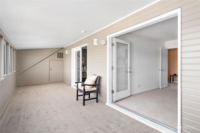 interior space featuring light colored carpet and wooden walls