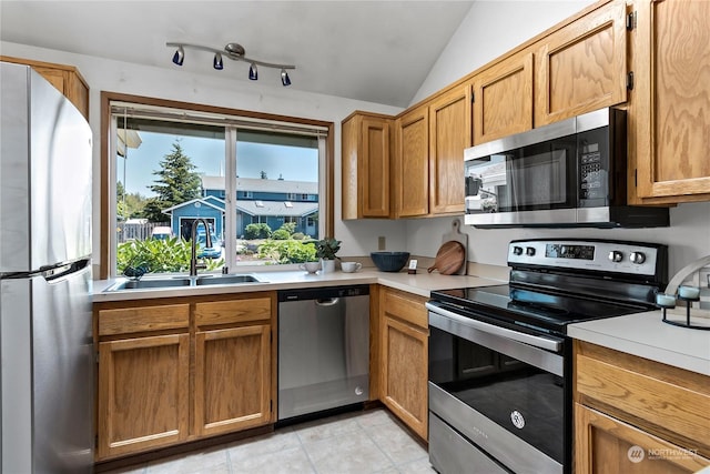 kitchen with sink, light tile patterned floors, vaulted ceiling, and appliances with stainless steel finishes