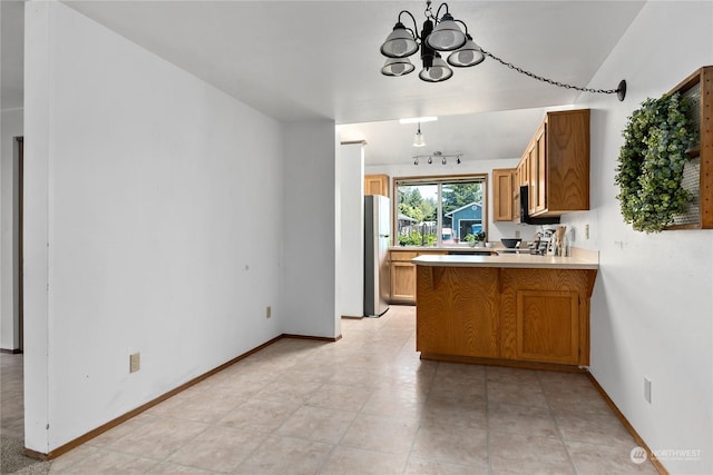 kitchen with range, stainless steel fridge, kitchen peninsula, and an inviting chandelier