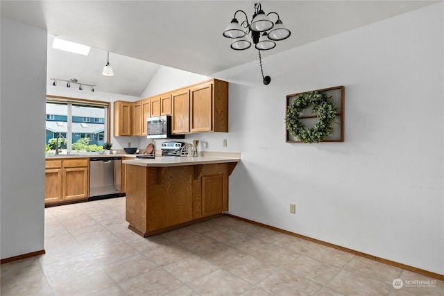 kitchen featuring lofted ceiling, appliances with stainless steel finishes, decorative light fixtures, kitchen peninsula, and a chandelier