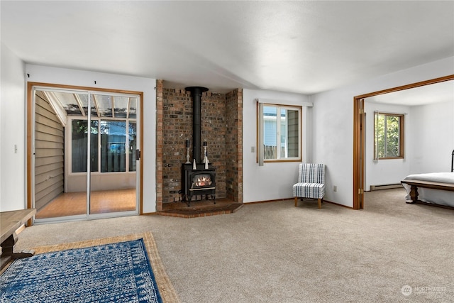 unfurnished living room with carpet flooring, a wood stove, and baseboard heating