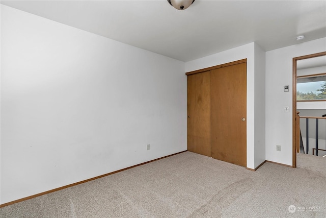 unfurnished bedroom with a closet and light colored carpet