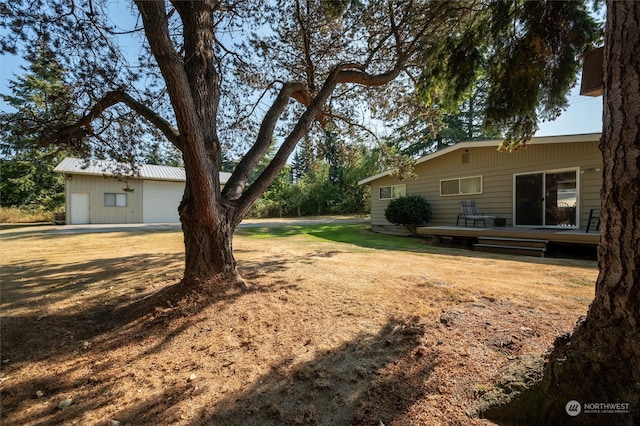 view of yard with an outdoor structure, a wooden deck, and a garage