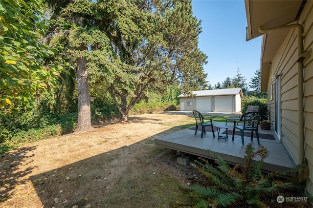 view of yard with an outdoor structure, a deck, and a garage