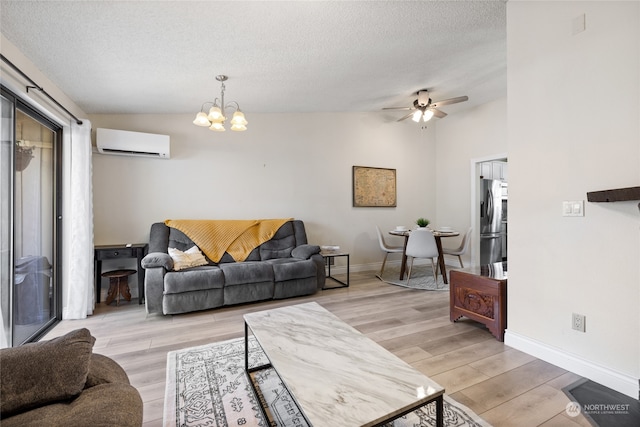 living room featuring ceiling fan with notable chandelier, a wall unit AC, vaulted ceiling, and light hardwood / wood-style floors