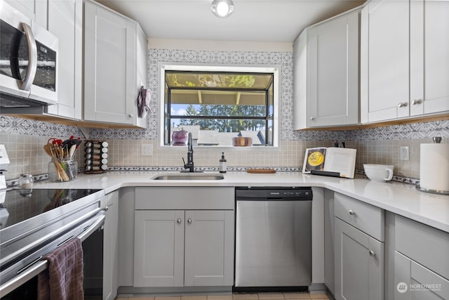 kitchen featuring tasteful backsplash, stainless steel appliances, sink, and light tile floors