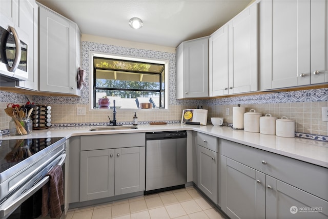 kitchen with gray cabinets, tasteful backsplash, appliances with stainless steel finishes, and sink