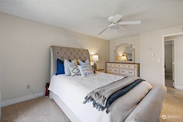 carpeted bedroom with ceiling fan and a textured ceiling