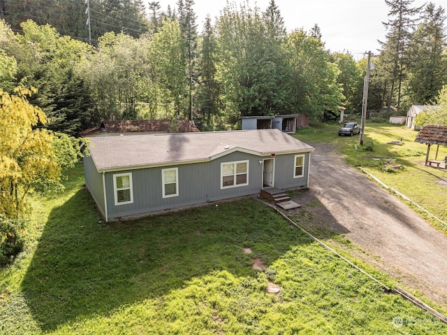 view of front of home with an outdoor structure and a front lawn