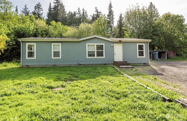 manufactured / mobile home featuring a front yard and a storage shed